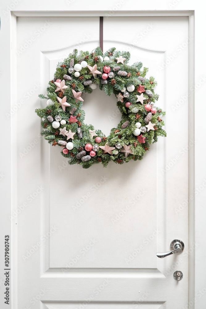 Beautiful Christmas wreath of fresh spruce on the white door. Entrance to the house. Christmas mood. Xmas tree. Beautiful Christmas wreath of fresh spruce on the white door. Entrance to the house. Christmas mood. Xmas tree.