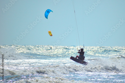 Beach activities at sea. Kitesurfing on the big waves.