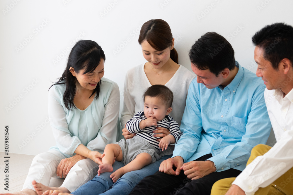  子供を抱っこして座っている3世代家族