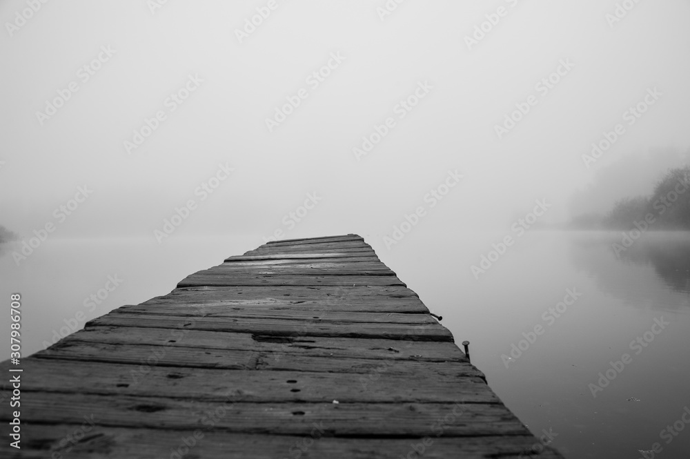 Wooden footbridge on lake with thick mist foggy air over water. Early chilly morning in late autumn. Empty place(copyspace) for text, quote or sayings. Concepts: peaceful, mindfullness, secret, nature