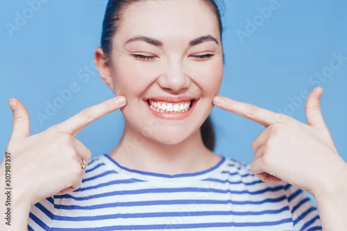 Obraz Smiling woman mouth with white healthy teeth on blue background.
