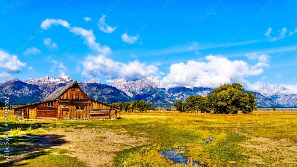 An abandoned Barn at Mormon Row with in the background cloud covered Peaks of the Grand Tetons In Grand Tetons National Park near Jackson Hole, Wyoming, United States