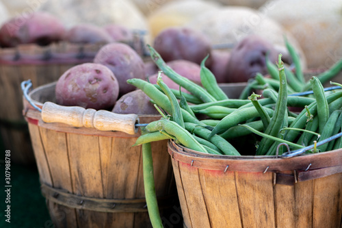 Wooden baskets containing fresh harvest of potatoes and green beans for sale at a local farmers market