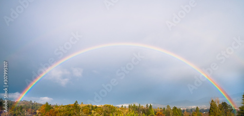 Full rainbow over treetops in the fall, in southern Oregon, USA