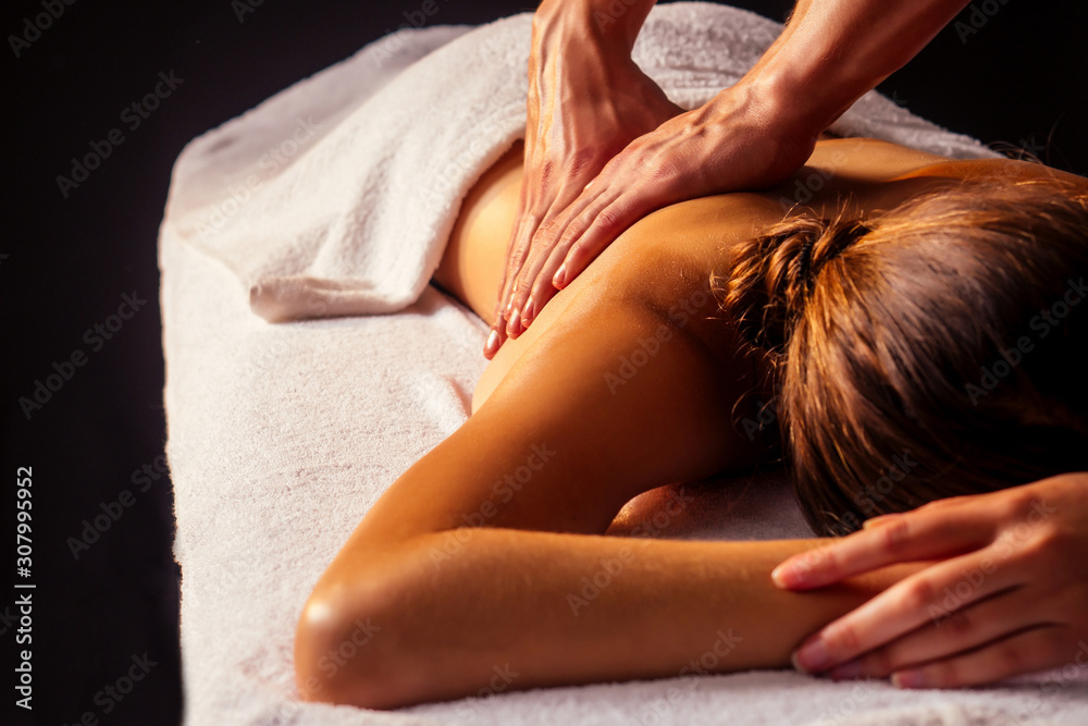 Fototapeta premium close-up masseur hands doing back massage to female client in spa center