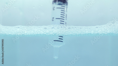 Water and bubbles with a syringe dip in blue water