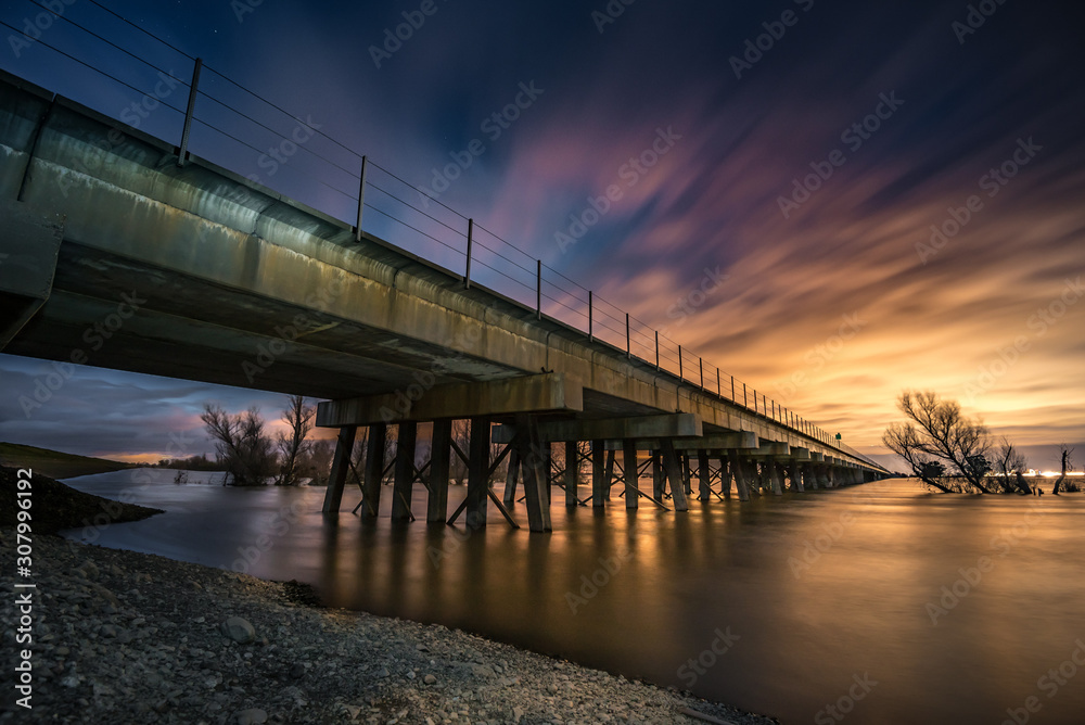 Train bridge over water at sunrise