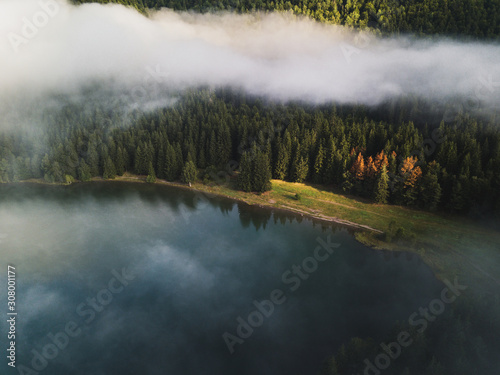 Aerial view of foggy cloud  evergreen forest  Volcanic lake at sunrise. Saint Anna Lake Romania Transylvania.