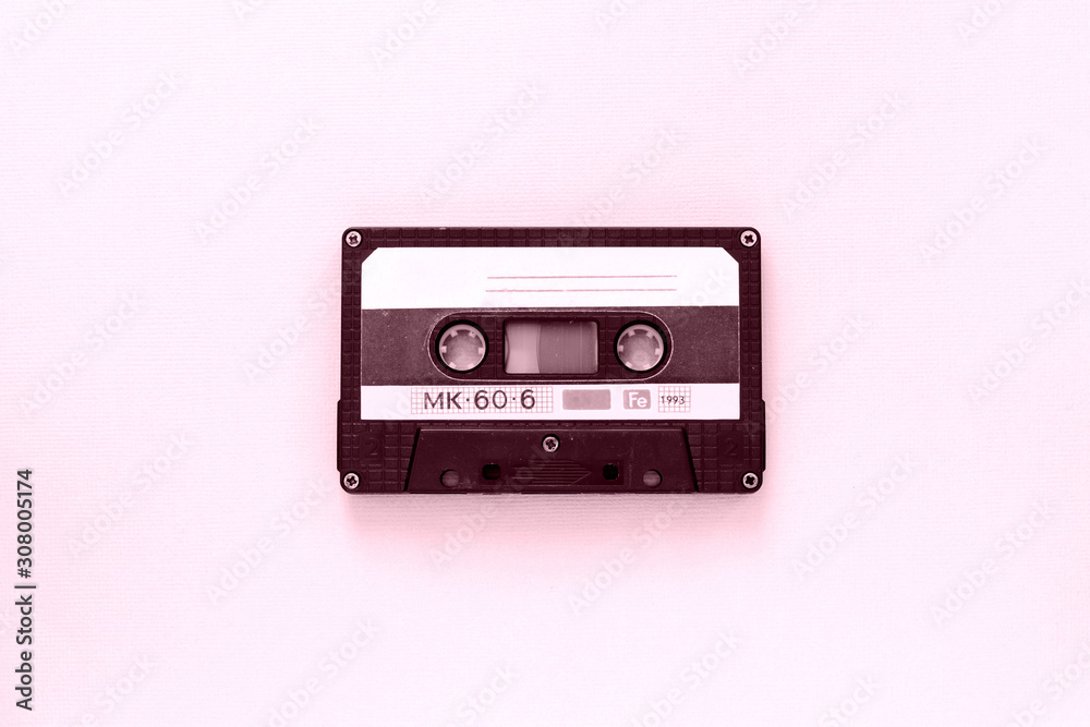 Old audio tape cassette close-up. Old technology concept. Pink color toned