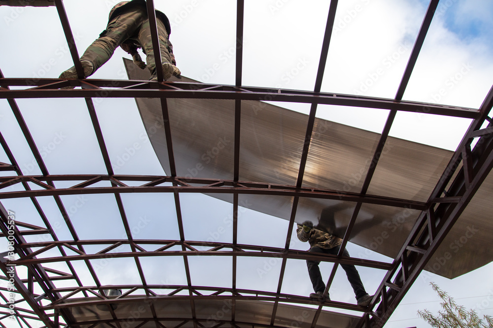 A worker mounts a metal canopy A worker mounts a metal canopy