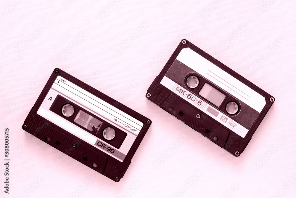 Fototapeta premium Two old audio tape cassettes close-up. Old technology concept. Pink color toned