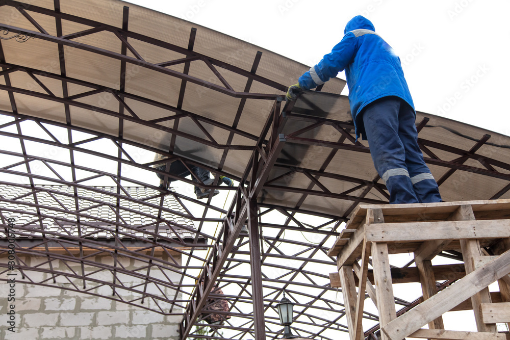 A worker mounts a metal canopy A worker mounts a metal canopy