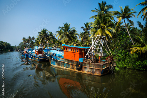 Ocean fishing boats along the canal Kerala backwaters shore with palm trees between Alappuzha and Kollam, India photo