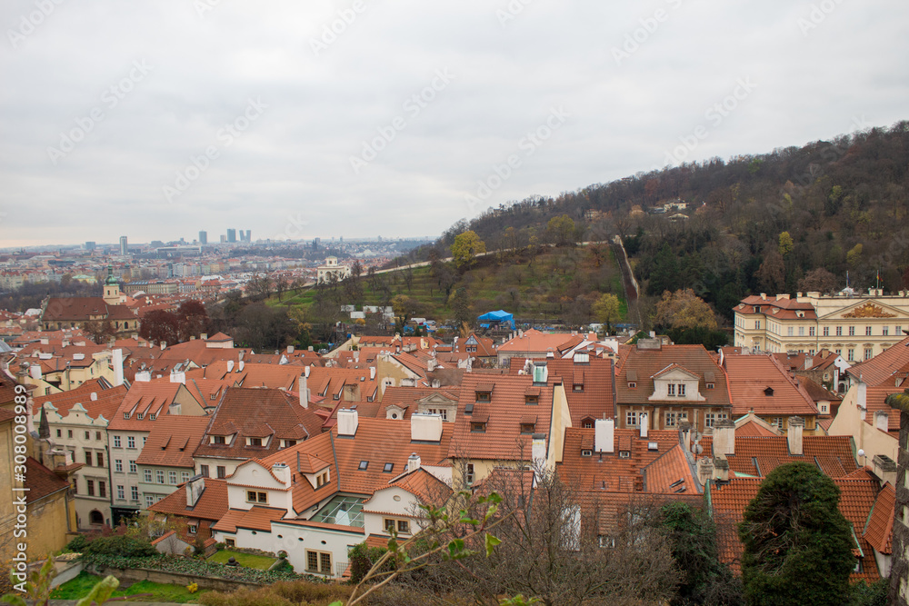 Fototapeta premium Panorama of the Czech city of Prague with tiled orange roofs from the observation deck of Prague Castle on a cloudy day on the eve of Christmas.