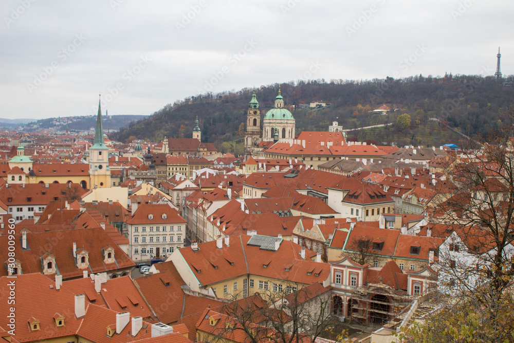 Obraz premium Panorama of the Czech city of Prague with tiled orange roofs from the observation deck of Prague Castle on a cloudy day on the eve of Christmas.