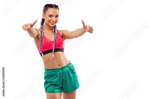 One cheerful fitness woman dancing and showing thumbs up isolated over white background © Admiral
