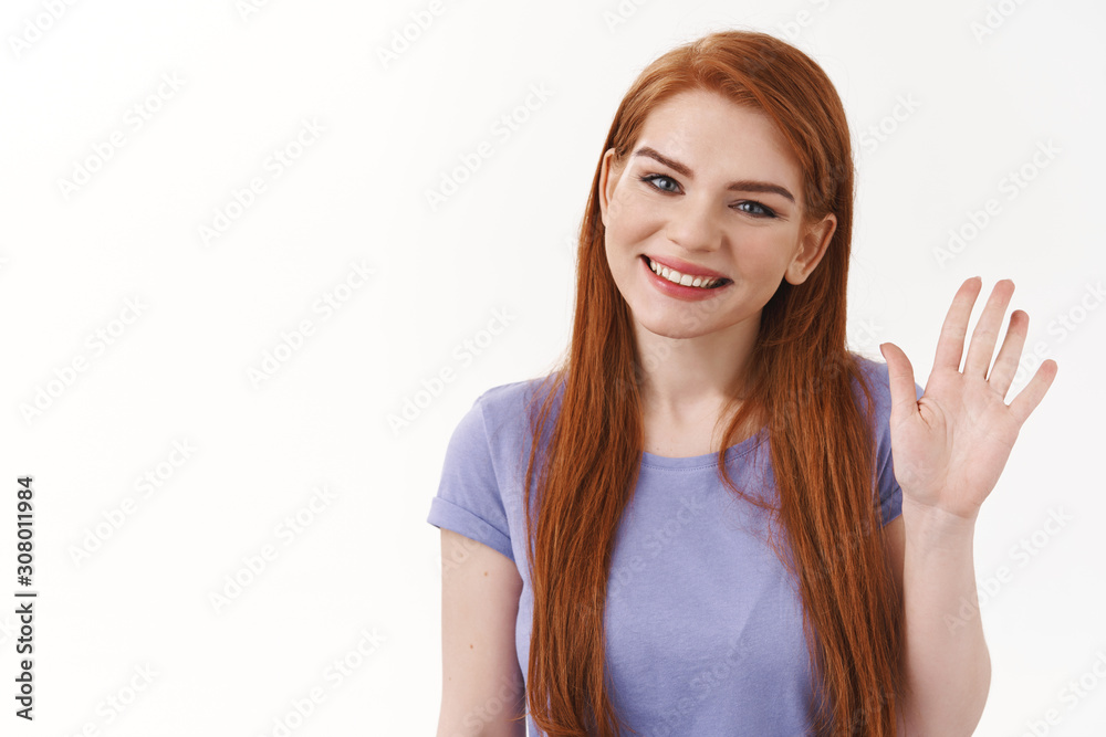 Close-up shot cheerful, friendly nice smiling redhead girl, waving raised arm in hello, hi gesture, tilt head and grinning, greeting someone, introduce herself first day new job, white background Close-up shot cheerful, friendly nice smiling redhead girl, waving raised arm in hello, hi gesture, tilt head and grinning, greeting someone, introduce herself first day new job, white background