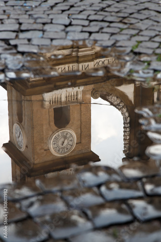 the bell tower of the ancient cathedral of Frascati, a stone's throw from Rome, is reflected in a puddle