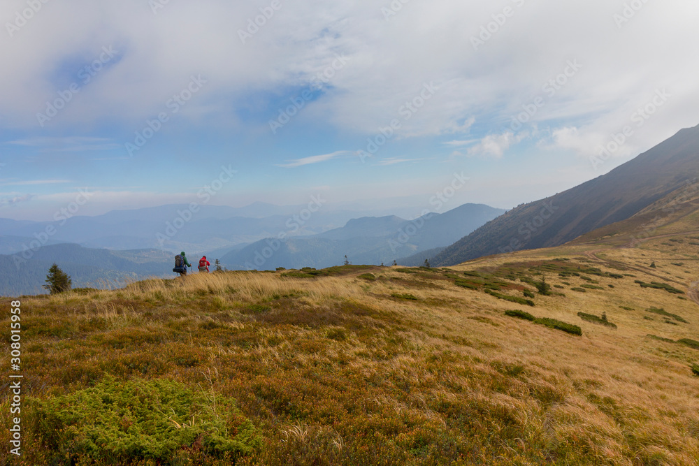 Tourists walk on a beautiful background autumn mountains. Karpaty Ukraine