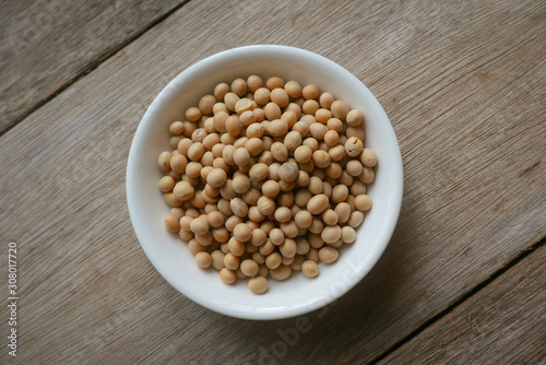 Soybeans in a white plate on wooden background. 