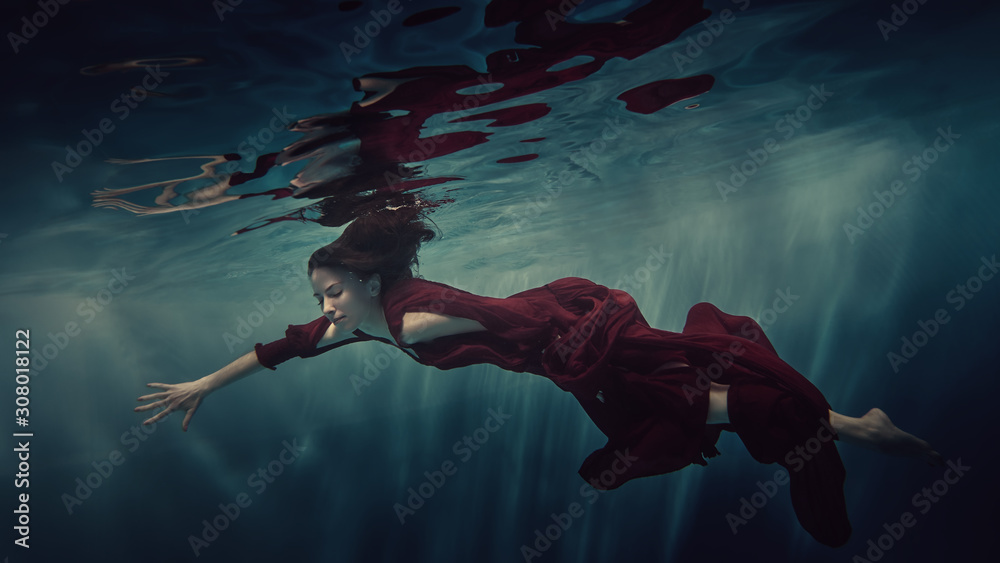 Portrait of a girl in a red dress under water