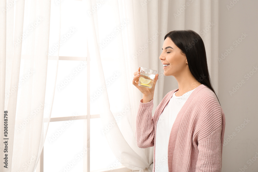 Beautiful young woman drinking fresh lemon water indoors Beautiful young woman drinking fresh lemon water indoors