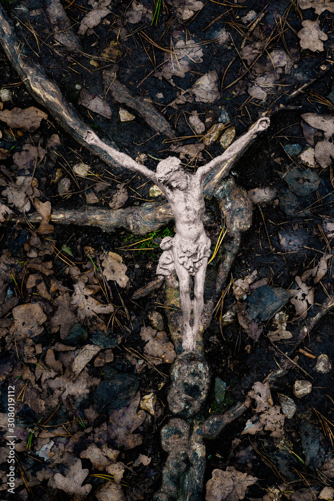 Fototapeta premium Metallic crucifix on tree roots on the ground
