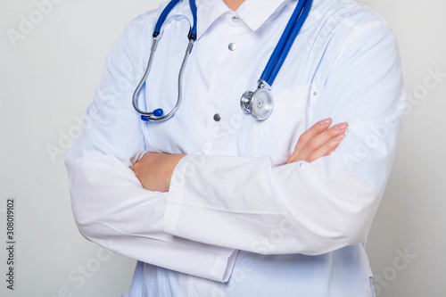 Close-up of a male doctor in a white coat with a stethoscope on his neck, standing with his arms crossed on his chest. One on a white background.