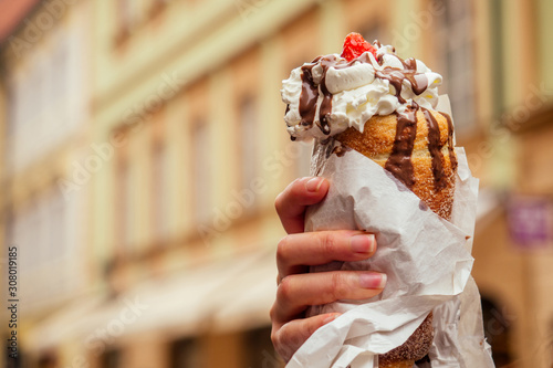 Photography appetite eats a traditional Czech sweet Trdelnik with vanilla cream and strawber