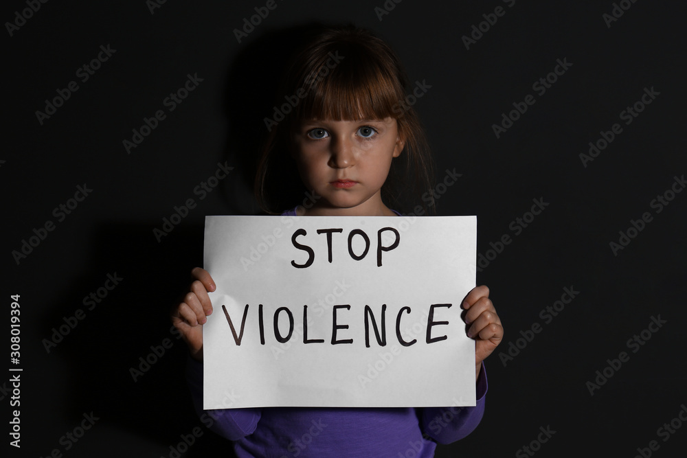 Abused little girl with sign STOP VIOLENCE near black wall Abused little girl with sign STOP VIOLENCE near black wall