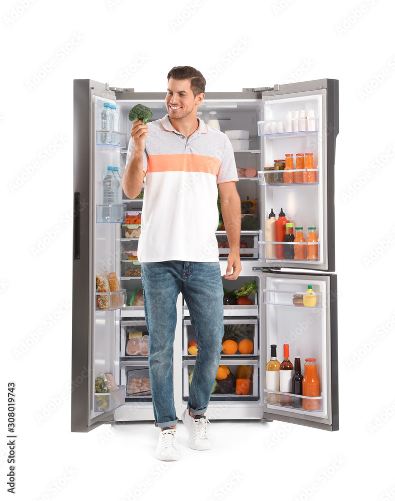 Man with broccoli near open refrigerator on white background Man with broccoli near open refrigerator on white background