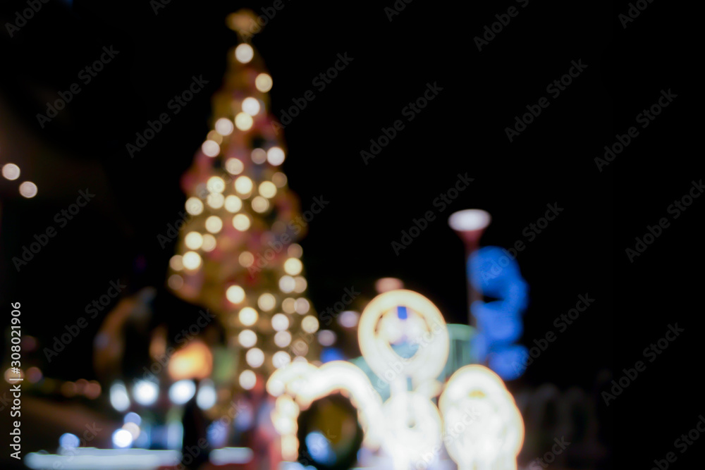 Blurred and bokeh view of Christmas tree and decorate led lighting front of shopping mall on Christmas night in urban city.