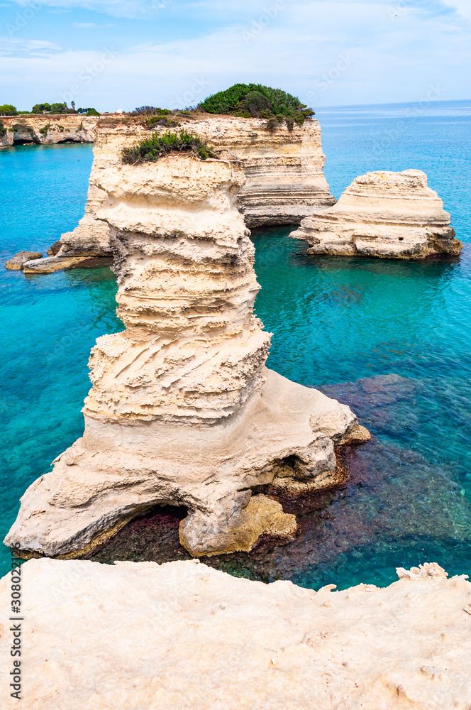 Fototapeta premium Torre Sant Andrea beach with its soft calcareous rocks and cliffs, sea stacks, small coves and the jagged coast landscape. Crystal clear water shape white stone create natural stacks. Melendugno Italy
