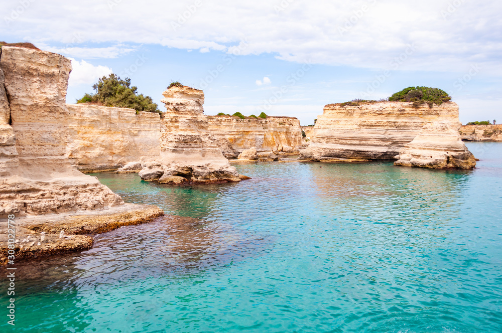 Torre Sant Andrea beach with its soft calcareous rocks and cliffs, sea stacks, small coves and the jagged coast landscape. Crystal clear water shape white stone creating natural arcs. Melendugno Italy