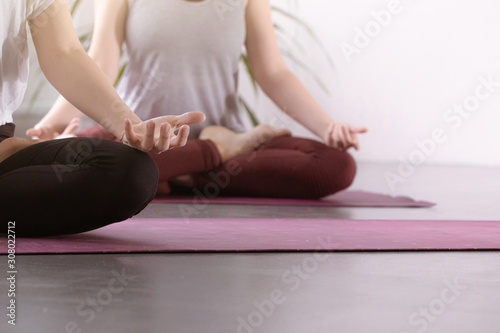 Yoga group concept. People meditating together, sitting back to back on windows background, copy space