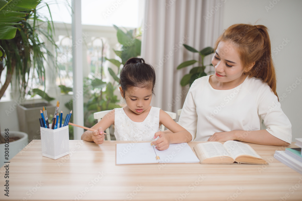 Asian mother and daughter doing home work together in living room Asian mother and daughter doing home work together in living room