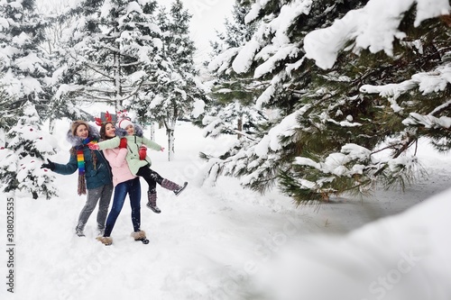 family-mother and two daughters having fun on the background of snow and forest. Winter entertainment