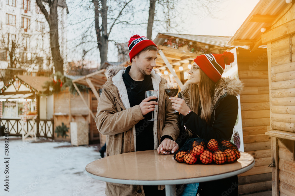 couple at the christmas market drink wine. man and woman in red hat
