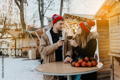 couple at the christmas market drink wine. man and woman in red hat