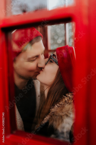 couple in love kisses in a red telephone box