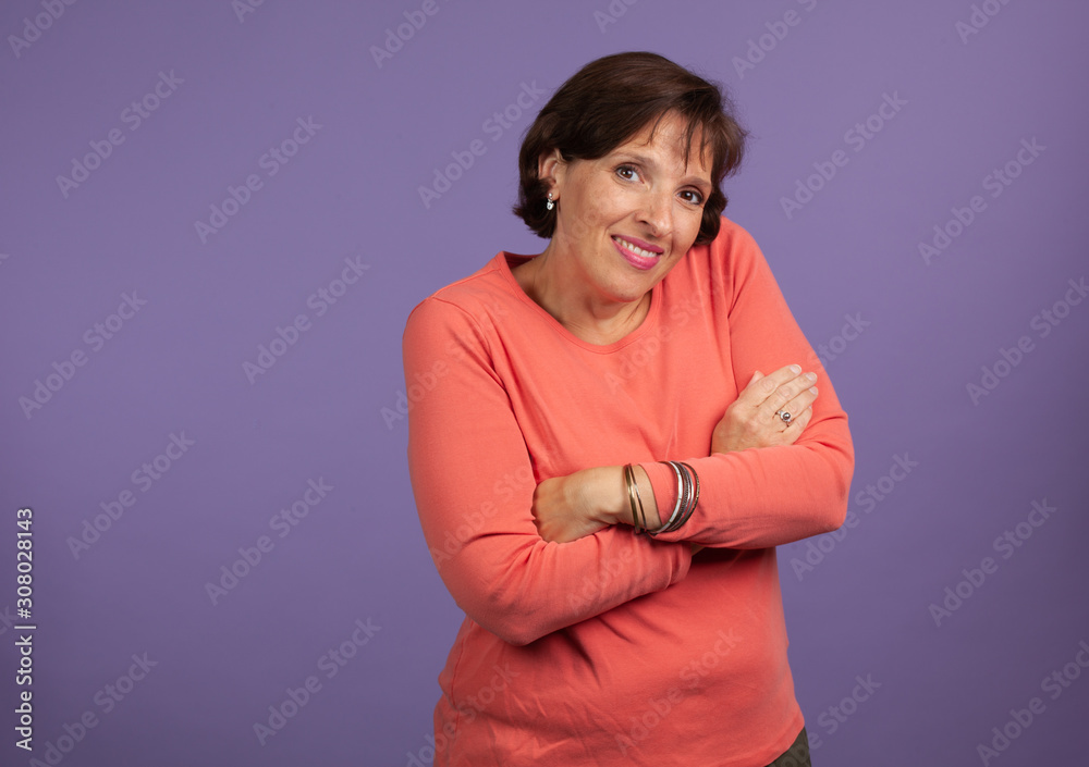 Middle age woman with arms folded on purple backgroud with copy space Middle age woman with arms folded on purple backgroud with copy space
