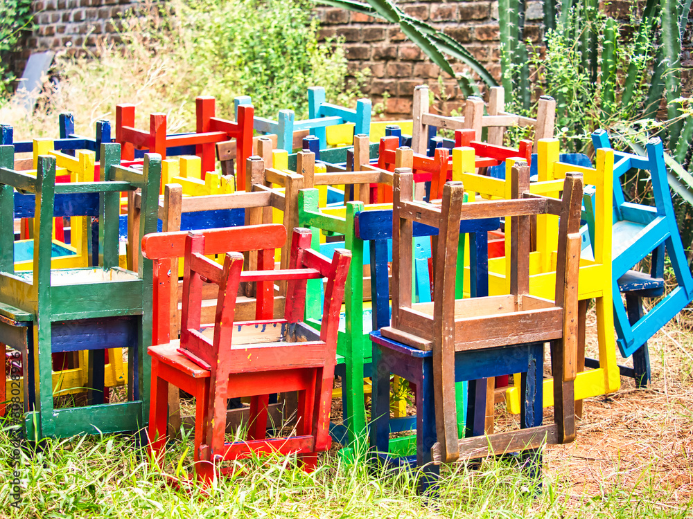 Stack of assorted colored wooden chairs in random disarray, full frame furniture background image