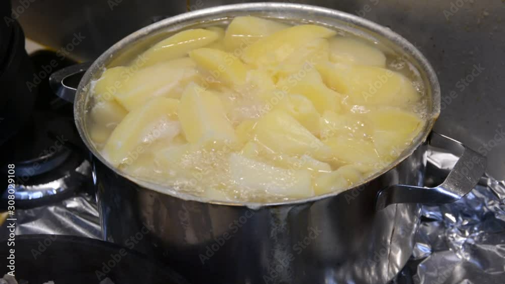 pieces of potatoes are boiled in a pan on a gas stove. pieces of potatoes are boiled in a pan on a gas stove.