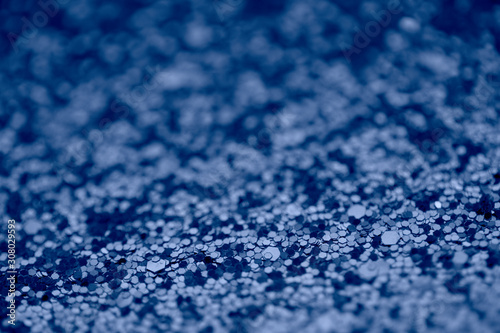 Abstract background with glitter in 2020 classic blue color. Modern sparkly backdrop with beautiful bokeh and copyspace.