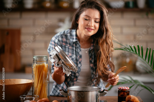 Young woman in kitchen. Beautiful woman making pasta. Cooking delicious dinner.