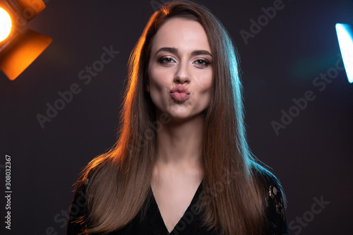 Εκτύπωση καμβά Close up beauty portrait of young beautiful woman in color backlight dressed in black who mug for the camera