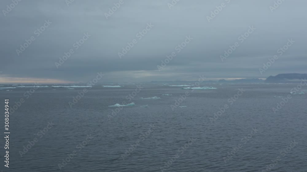 Handheld, high angle, wide shot from inside a moving boat of icebergs in a vast sea. Handheld, high angle, wide shot from inside a moving boat of icebergs in a vast sea.