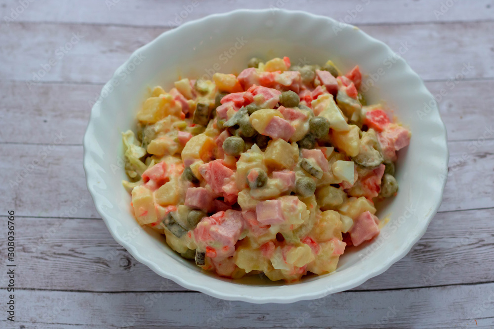 Olivier vegetable salad in a glass bowl of home cooking, closeup photo. Olivier vegetable salad in a glass bowl of home cooking, closeup photo.
