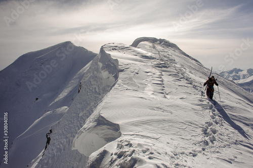 Skier with skiing equipment walks down the mountain © fesenko