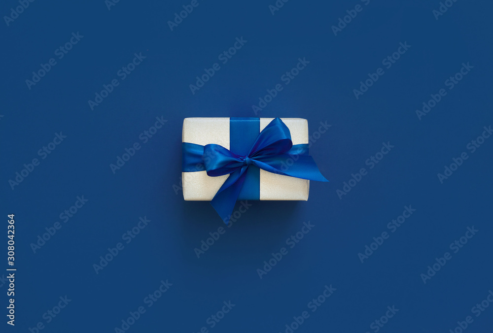 Festive Christmas decor on a blue classic background. Silver gift boxes, sparkles, ribbons, bows. Color of the year 2020.